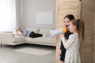 Cute little children with megaphone waking up their father at home
