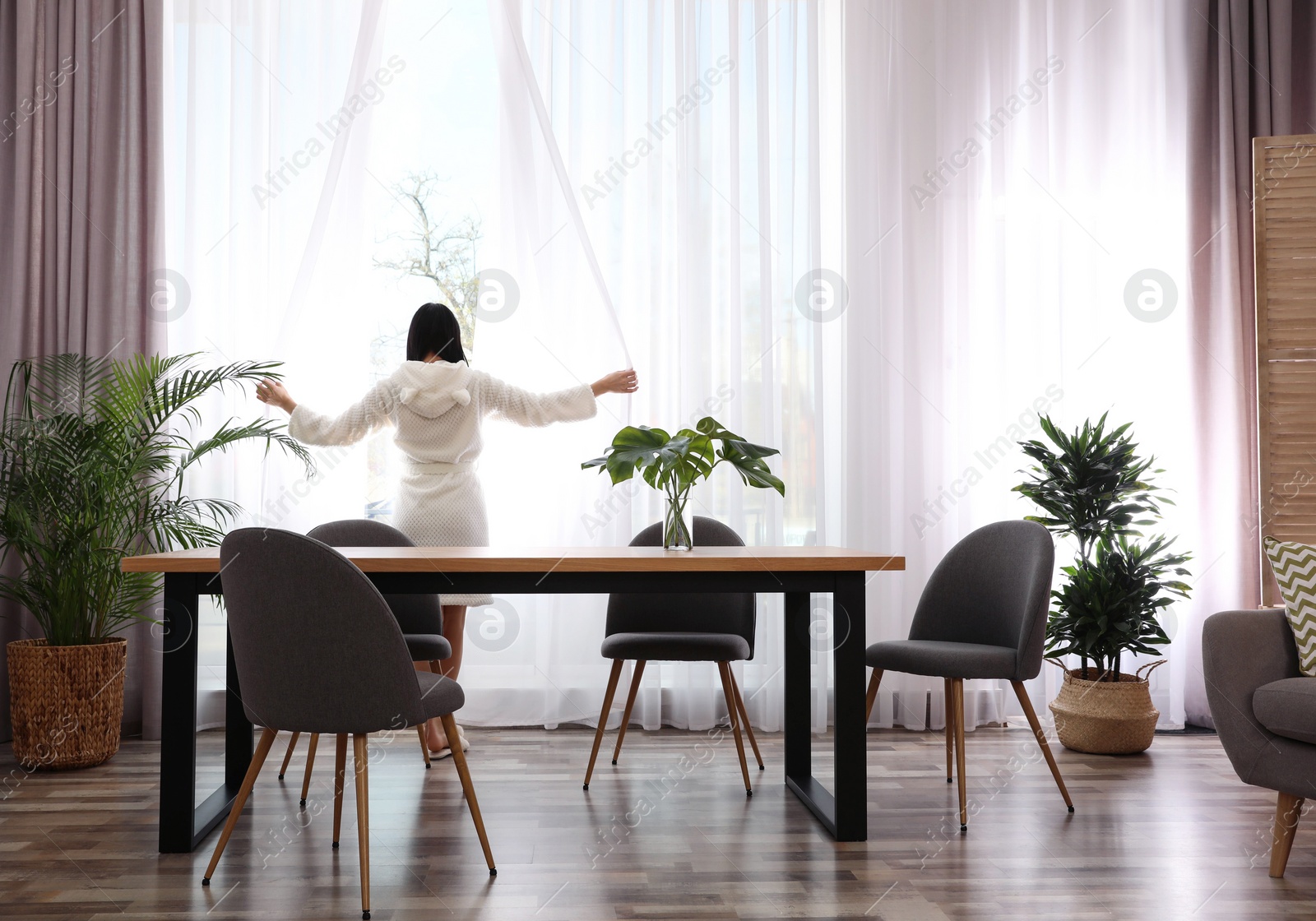 Photo of Woman near window in room decorated with plants. Home design ideas