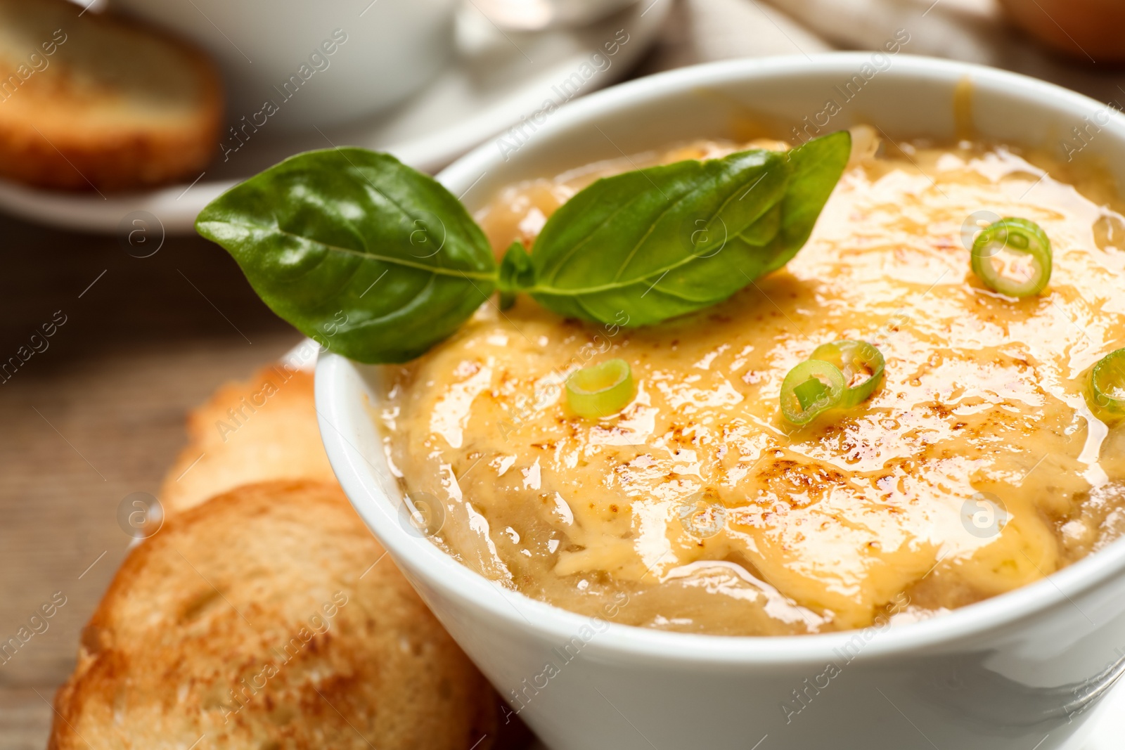 Photo of Tasty homemade french onion soup served in ceramic bowl, closeup