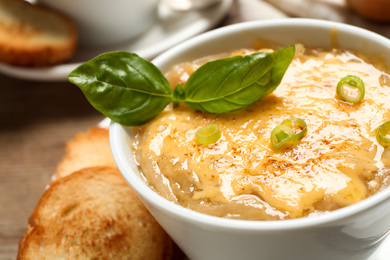 Photo of Tasty homemade french onion soup served in ceramic bowl, closeup