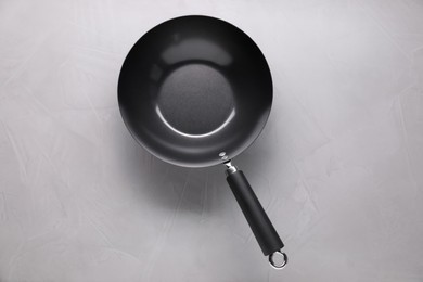 Empty iron wok on grey textured table, top view. Chinese cookware