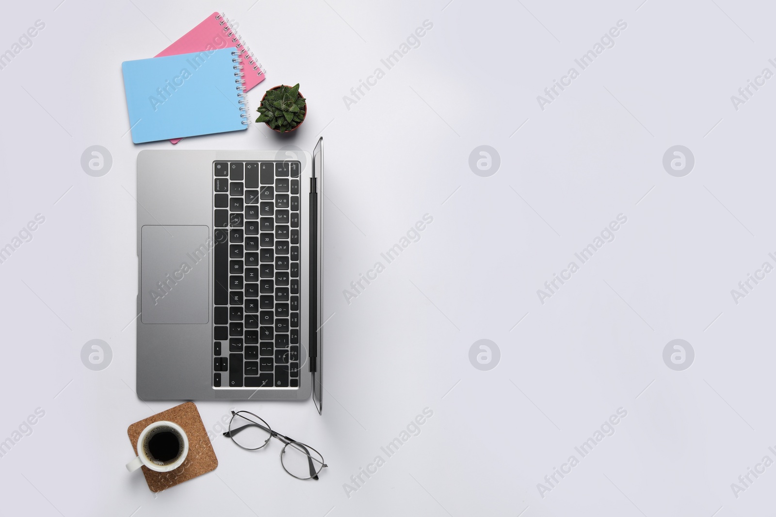 Photo of Modern laptop, notebooks and cup of coffee on white table, flat lay. Space for text