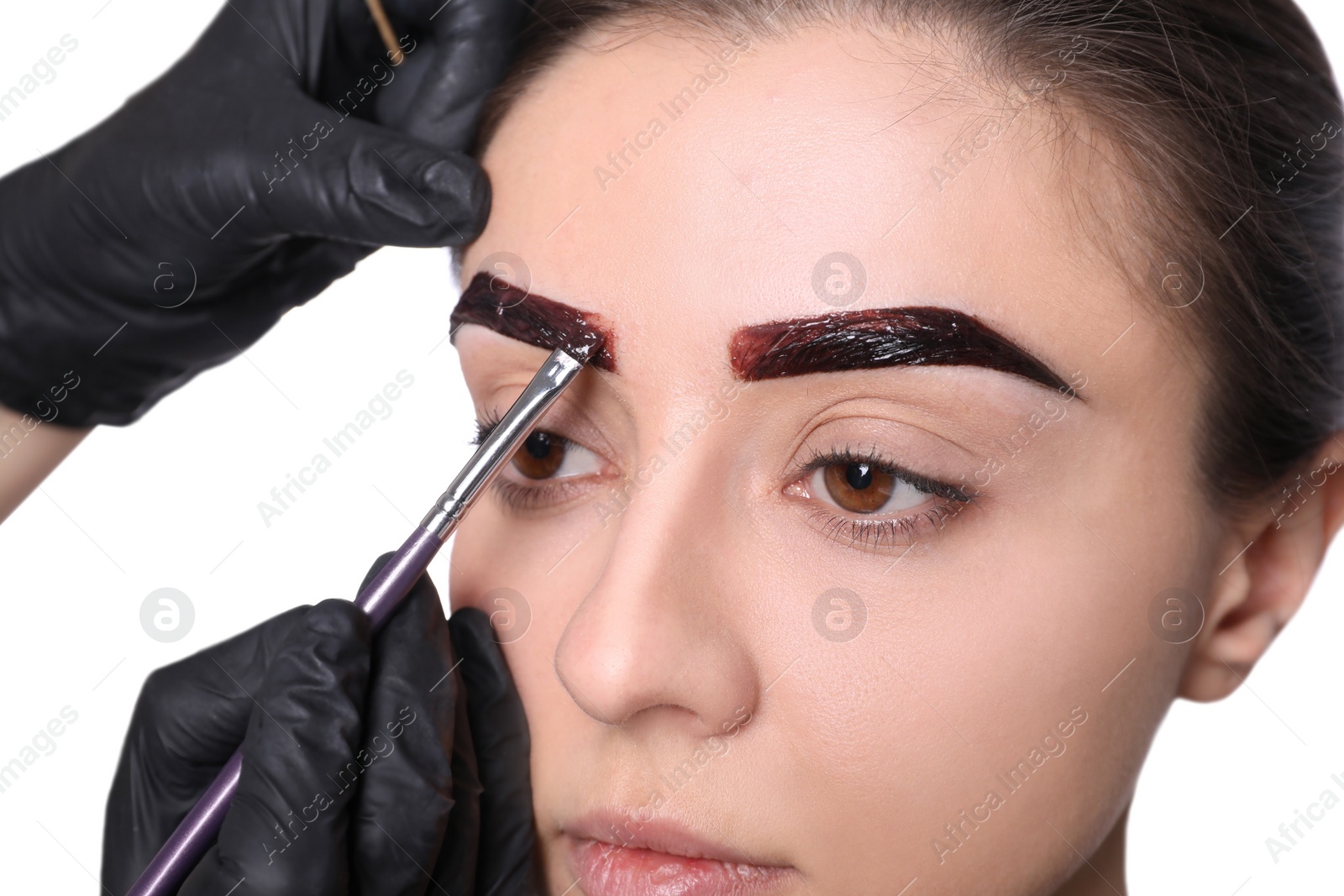 Photo of Beautician applying tint during eyebrows correction procedure on white background, closeup