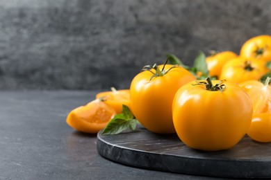 Photo of Fresh ripe yellow tomatoes on black table, closeup. Space for text