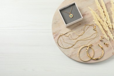 Photo of Different elegant bijouterie and dry plants on white wooden table, top view. Space for text