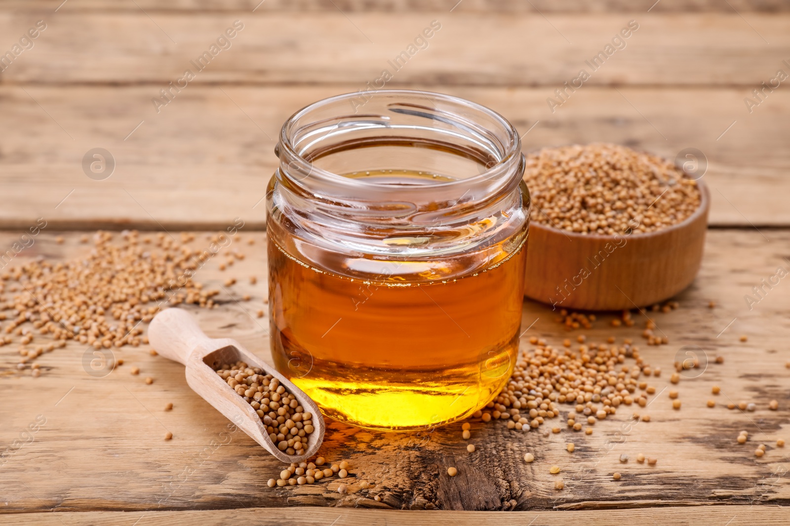 Jar of natural oil and mustard seeds on wooden table Photo of Jar of natural oil and mustard seeds on wooden table