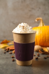 Photo of Paper cup with tasty pumpkin spice latte on grey table