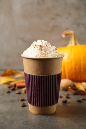 Paper cup with tasty pumpkin spice latte on grey table