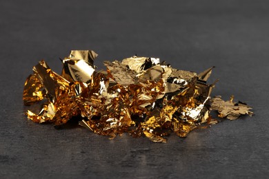 Photo of Pieces of edible gold leaf on textured table, closeup