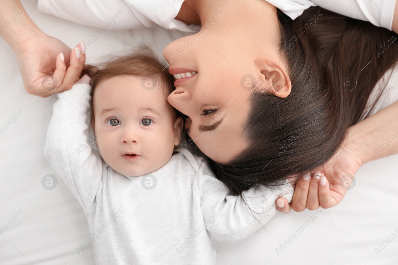 Photo of Portrait of mother with her cute baby lying on bed, top view