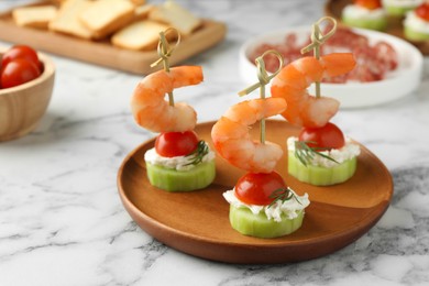 Photo of Tasty canapes with shrimps, vegetables and cream cheese on white marble table