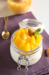 Photo of Tasty peach dessert with yogurt in glass jar on table