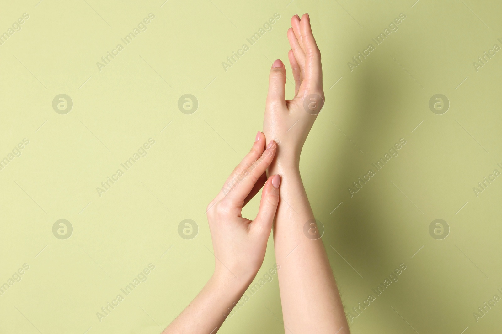 Photo of Woman applying cream on her hand against green background, closeup