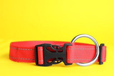 Photo of Red dog collar on yellow background, closeup. Space for text