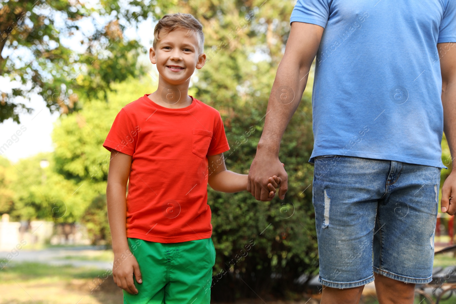 Photo of Little boy and his father holding hands outdoors. Family weekend