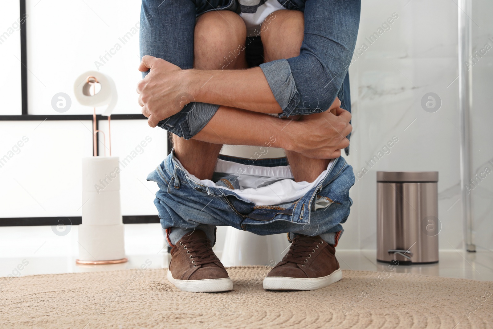 Photo of Man suffering from hemorrhoid on toilet bowl in rest room, closeup