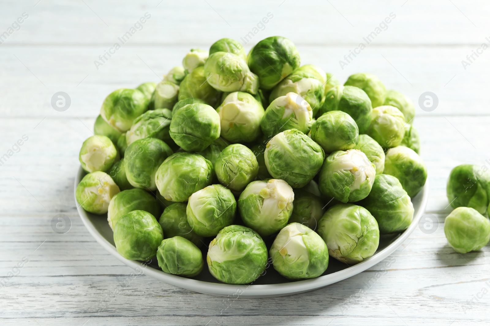 Photo of Plate with fresh Brussels sprouts on wooden background