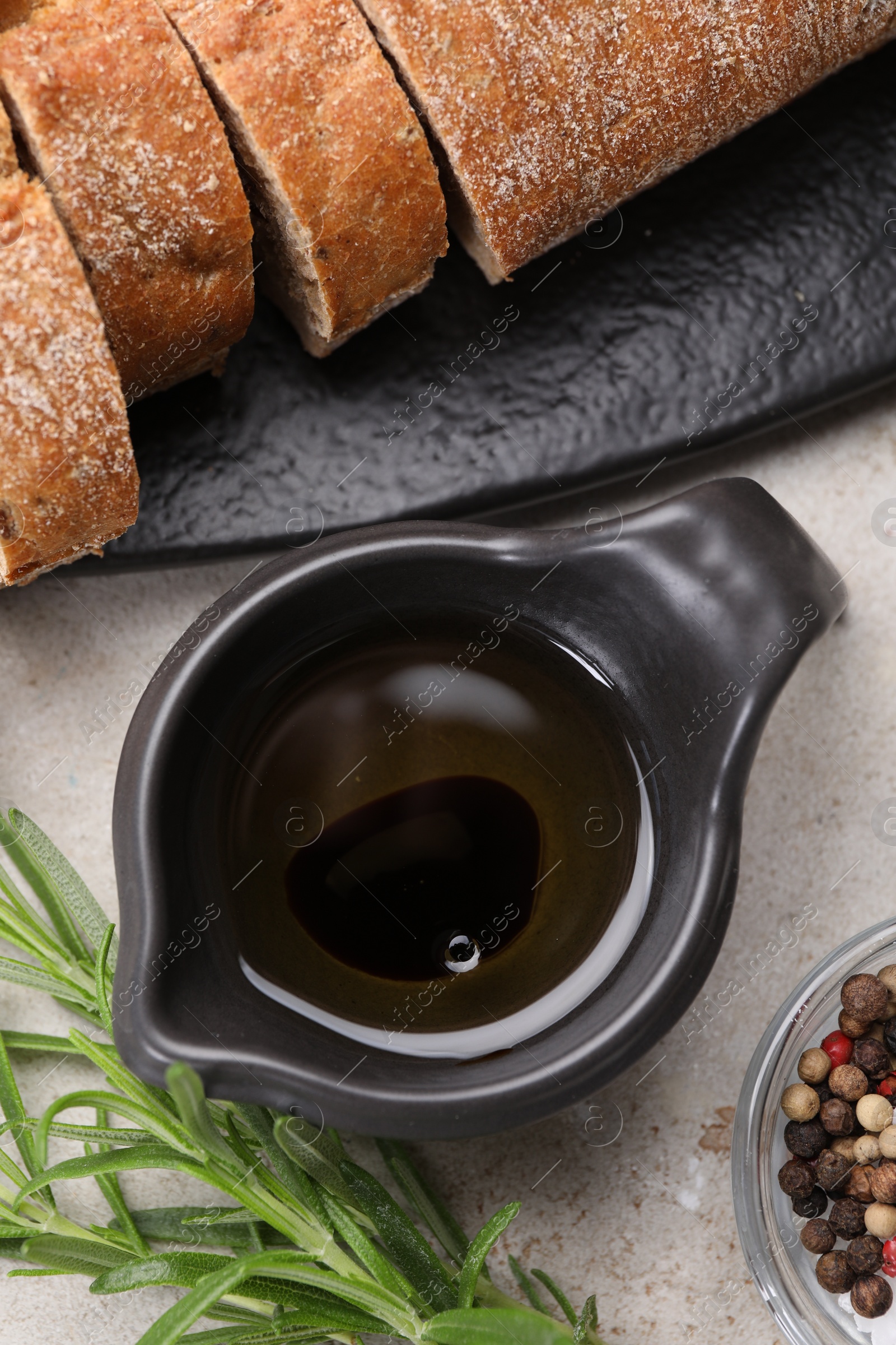 Photo of Saucepan of organic balsamic vinegar with oil, spices and bread slices on beige table, flat lay