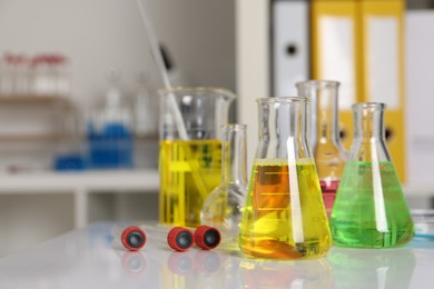 Laboratory analysis. Different glassware with liquids on white table indoors, space for text