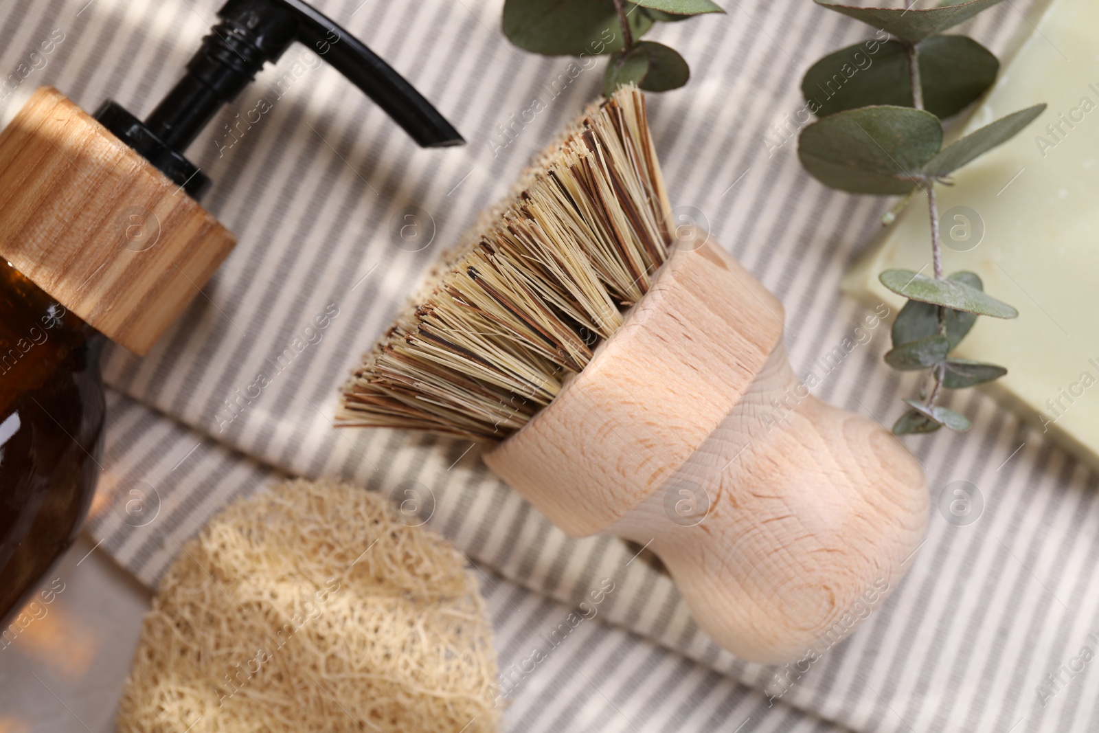 Photo of Cleaning brush, sponge, dispenser and eucalyptus leaves on table, top view