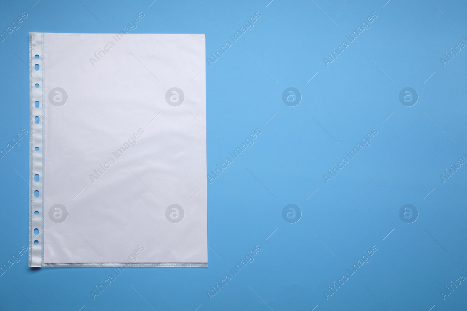 Photo of Punched pocket with paper sheet on light blue background, top view. Space for text