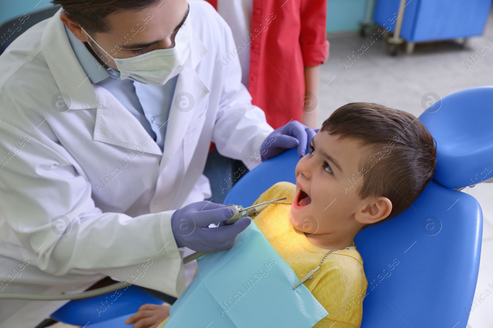 Photo of Professional dentist working with little patient in modern clinic