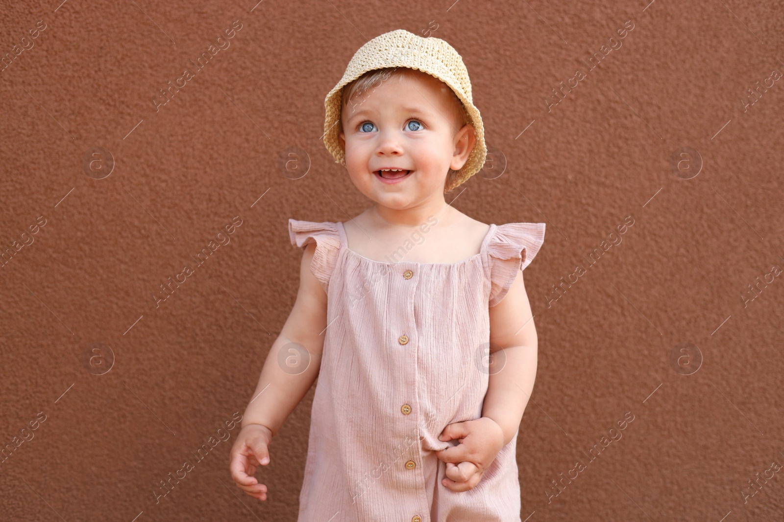 Photo of Cute little girl wearing stylish clothes near brown wall