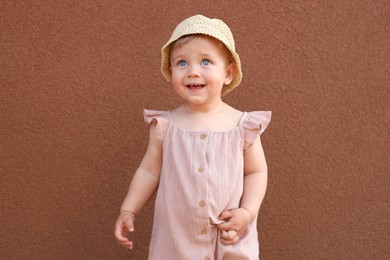 Photo of Cute little girl wearing stylish clothes near brown wall