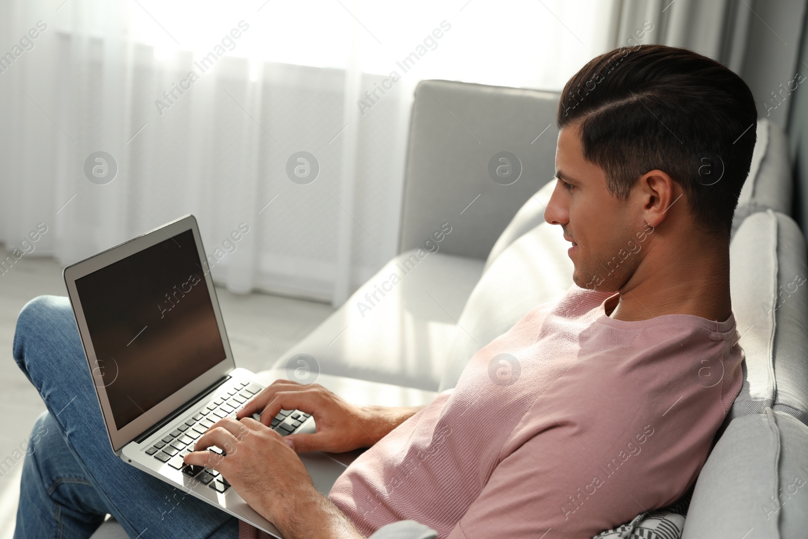Photo of Man using laptop for search on sofa at home