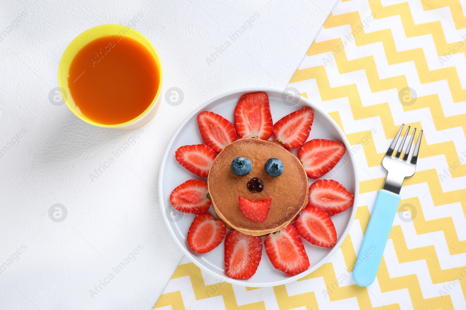 Photo of Tasty pancakes served with berries and juice on white table, flat lay. Creative idea for kids breakfast