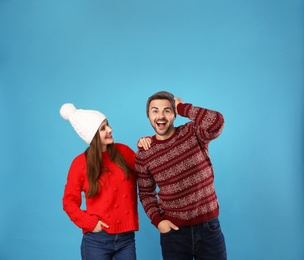 Photo of Couple wearing Christmas sweaters and hats on blue background