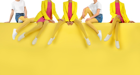 Image of Women wearing yellow tights and stylish shoes sitting on color background, closeup 