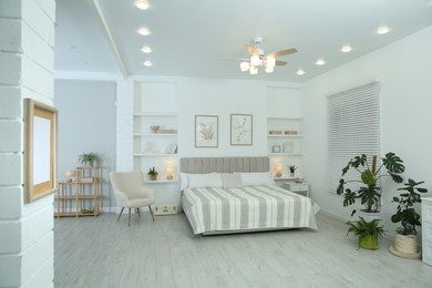 Photo of Comfortable furniture, ceiling fan, houseplants and accessories in stylish bedroom