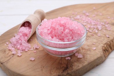 Photo of Bowl and scoop with pink sea salt on white wooden table, closeup