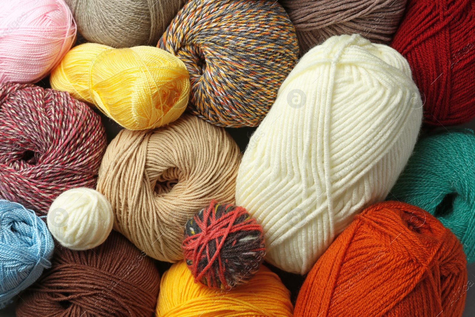 Photo of Different balls of woolen knitting yarns as background, top view