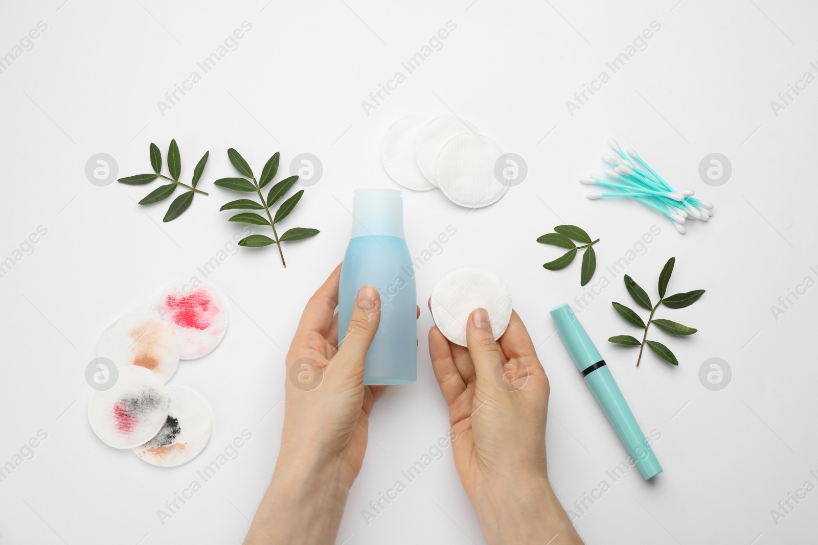 Photo of Woman holding makeup removal product and cotton pad on white background, top view