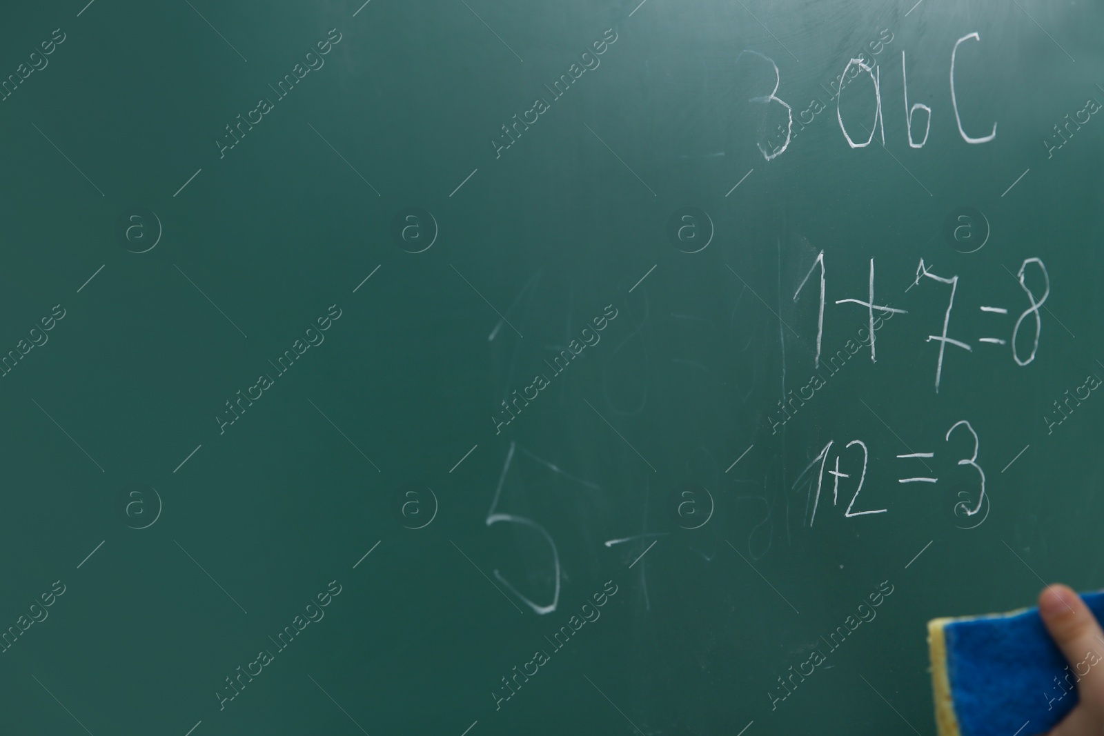 Photo of Little child wiping math sums from chalkboard, closeup. Space for text