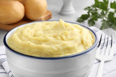 Photo of Bowl of tasty mashed potatoes served on grey table, closeup