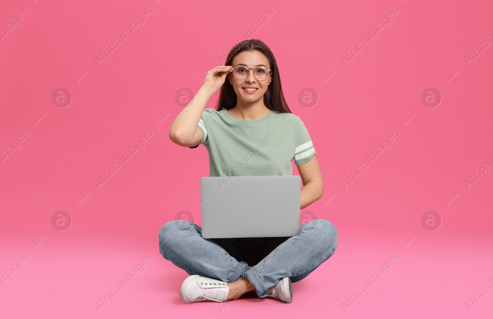 Photo of Young woman with modern laptop on pink background