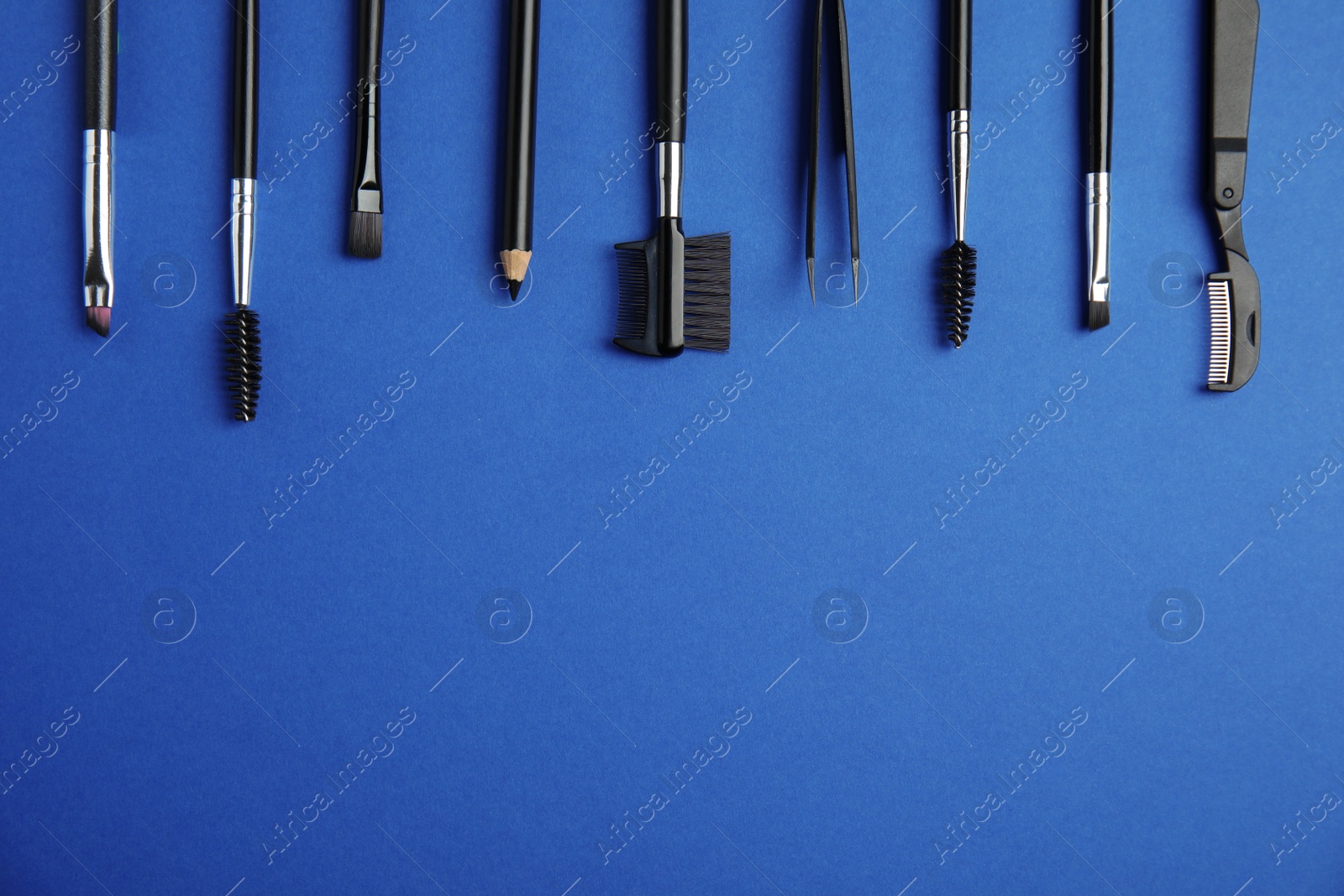Photo of Set of professional eyebrow tools on blue background, flat lay. Space for text