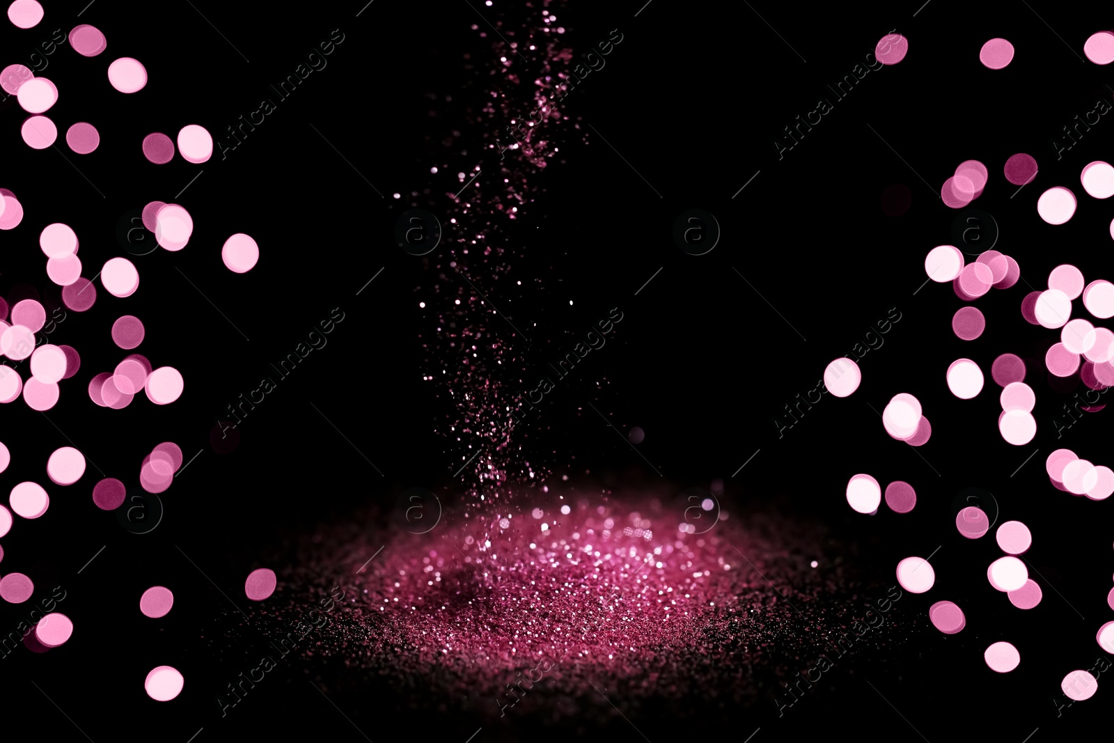 Photo of Sprinkling rose glitter on black background, bokeh effect