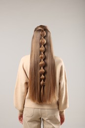 Woman with braided hair on grey background, back view