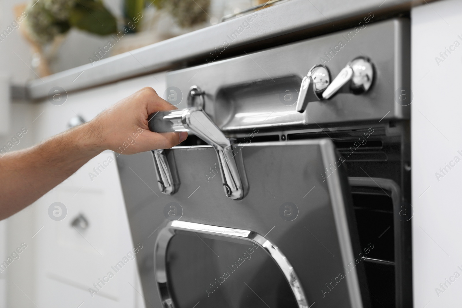 Photo of Man using modern oven in kitchen, closeup