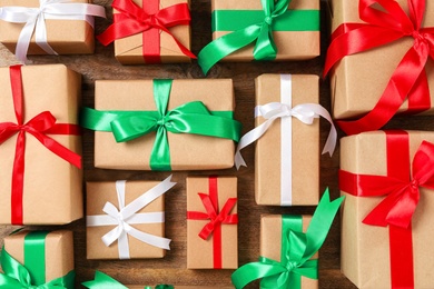 Photo of Christmas gift boxes with bows on wooden background, flat lay