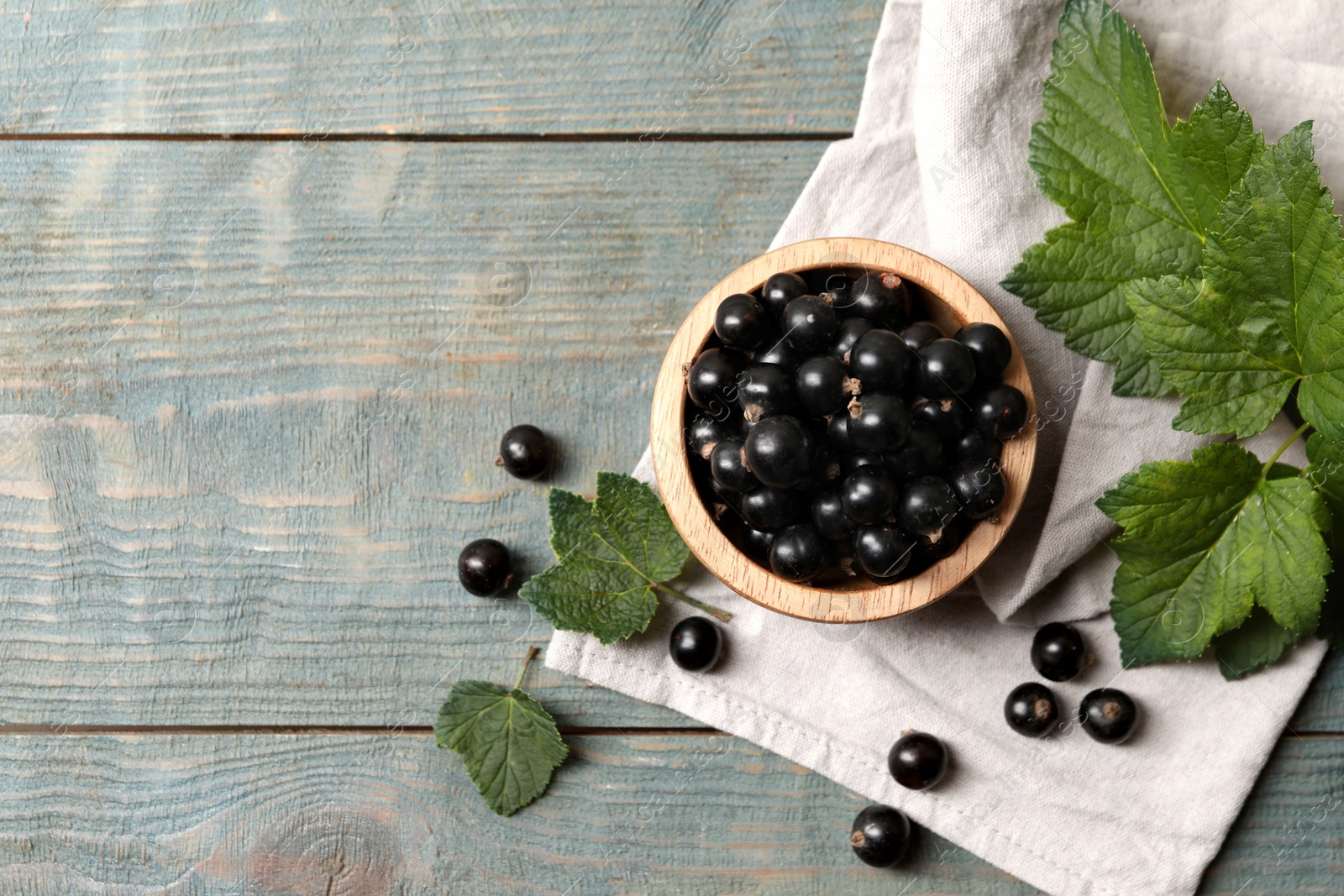 Photo of Ripe blackcurrants and leaves on wooden rustic table, flat lay. Space for text