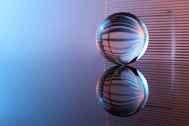 Photo of Transparent glass ball on mirror surface. Space for text