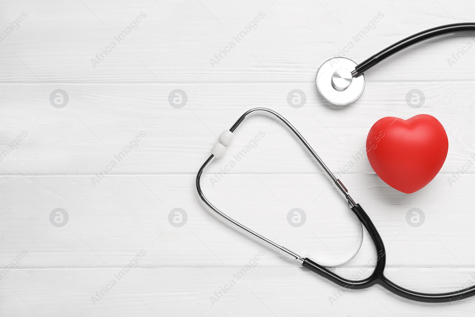 Photo of Stethoscope, red decorative heart and space for text on white wooden background, flat lay. Cardiology concept