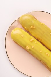 Delicious eclairs covered with glaze on white background, top view