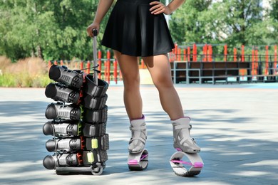 Woman with kangoo jumping boots on hand trolley outdoors, closeup