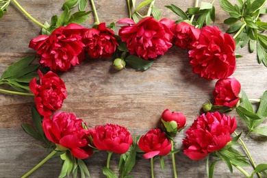 Flat lay composition with beautiful blooming peonies on wooden background